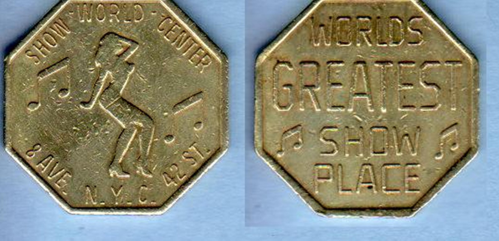 Two views of the same worn octagonal brass token photographed side by side on a pale blue ground. The obverse is struck with a dancing figure, musical notes, and lettering around the rim reading SHOW WORLD CENTER, 8 AVE., 42 ST., N.Y.C. The reverse is struck WORLDS GREATEST SHOW PLACE between two musical notes. The metal is scuffed and rubbed bright at the raised edges.