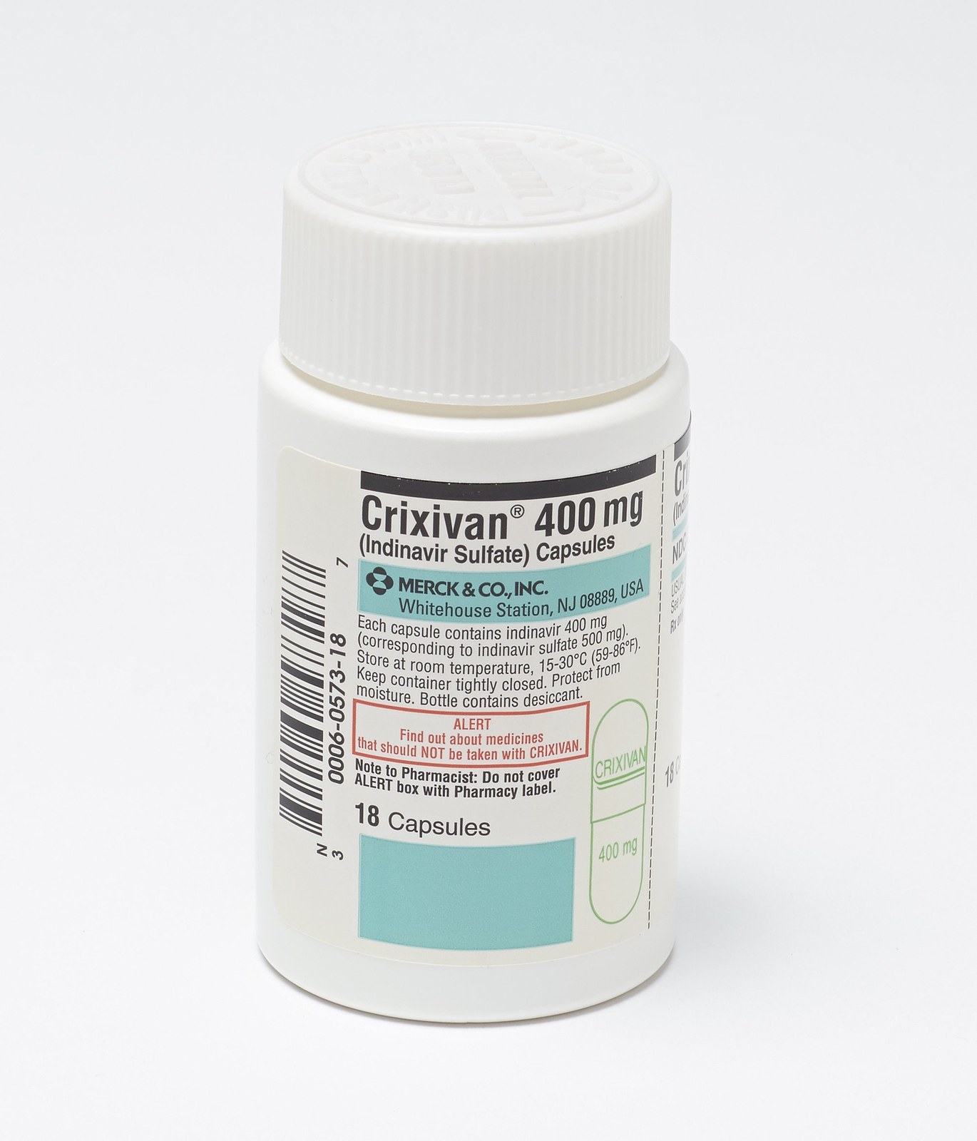Studio photograph of a small white plastic pill bottle standing on a plain white background. The printed label reads Crixivan 400 mg, indinavir sulfate capsules, Merck & Co., Inc., Whitehouse Station, NJ, 18 capsules, with storage instructions, a barcode, and a red-outlined box headed ALERT warning about medicines that should not be taken with the drug. A white ribbed child-resistant cap sits on top; a second panel of the wrapped label is visible curving away around the side of the bottle.